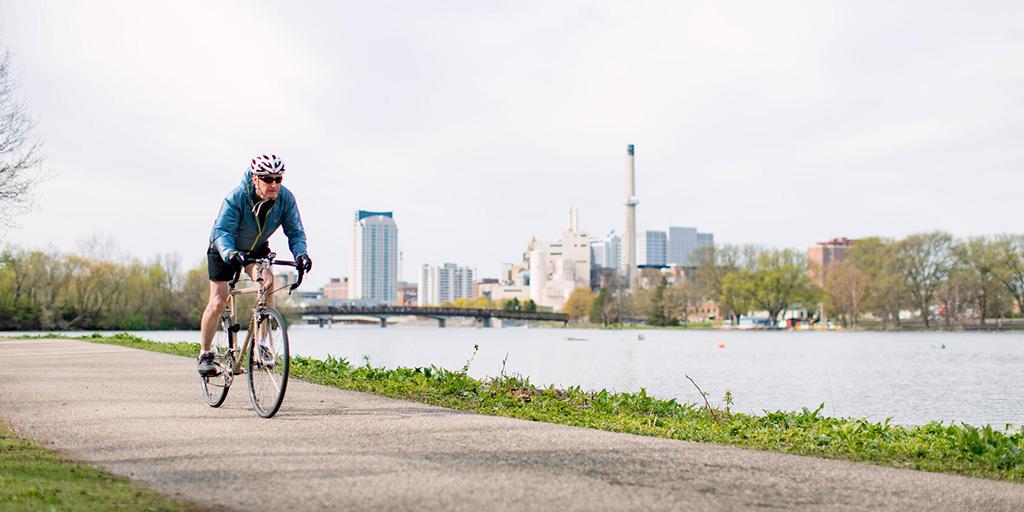 Individual biking outside along a path next to the river