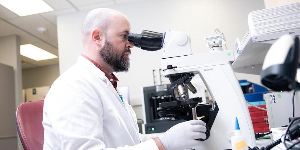 A Mayo Clinic medical laboratory scientist uses a microscope