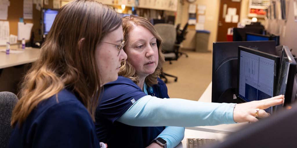 An instructor guides a technician through computer readings during a Polysomnography (sleep study) clinical lab session for the Clinical Neurophysiology Technology (CNT) program.
