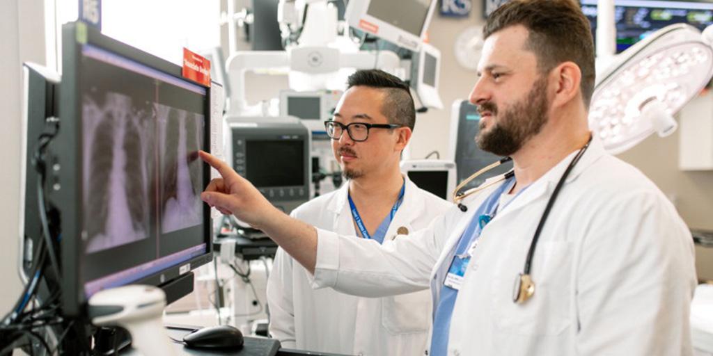 Two fellows in a surgical suite with in front of a computer screen