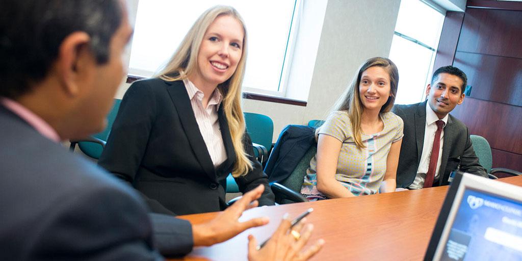 Medical providers sitting at a conference table discussing case studies for the day