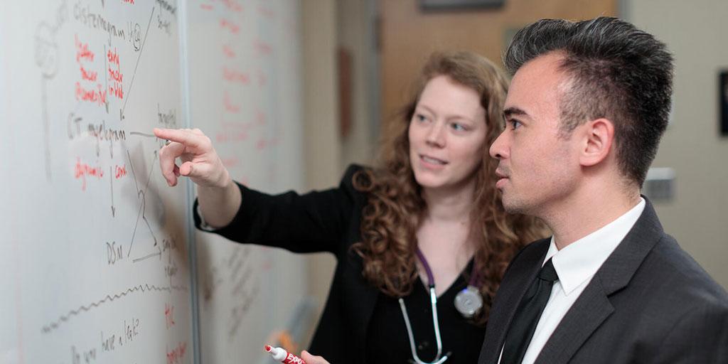 Two fellows standing and writing on a whiteboard