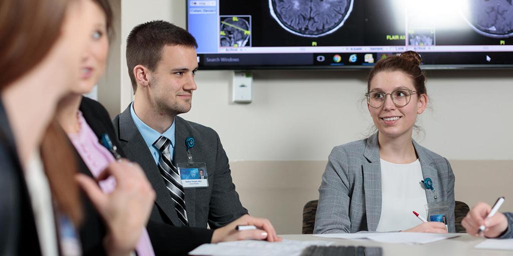 Group of students in a classroom setting, discussing what is on the smart board