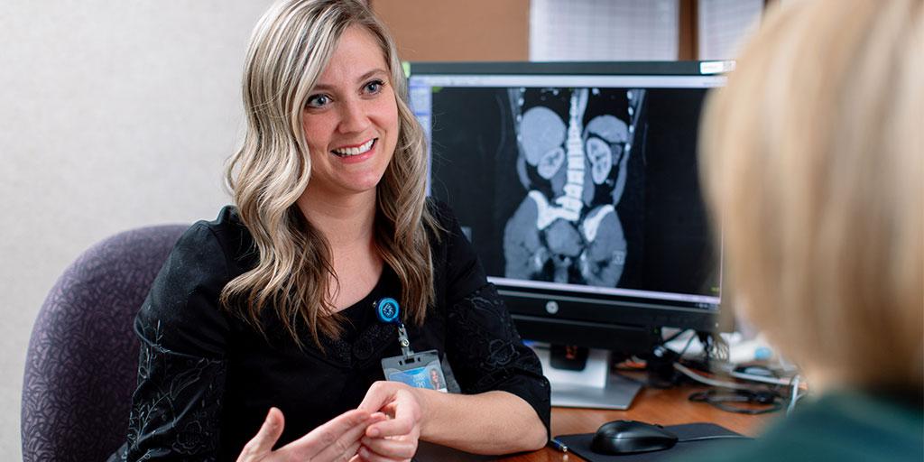 A PA or NP discussing urology case with patients in medical office.