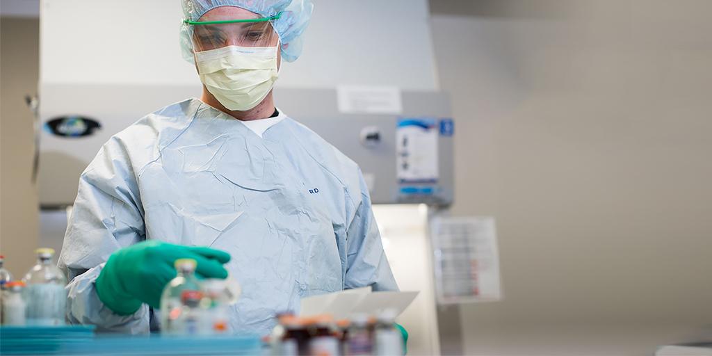 Pharmacy technician handling medications in protective gear