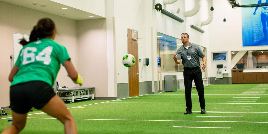 Sports medicine physical therapist working in a gym type atmosphere with a patient on soccer skills