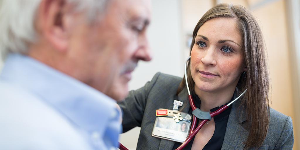 Physician assistant student checking heart lungs using a stethoscope during an exam 
