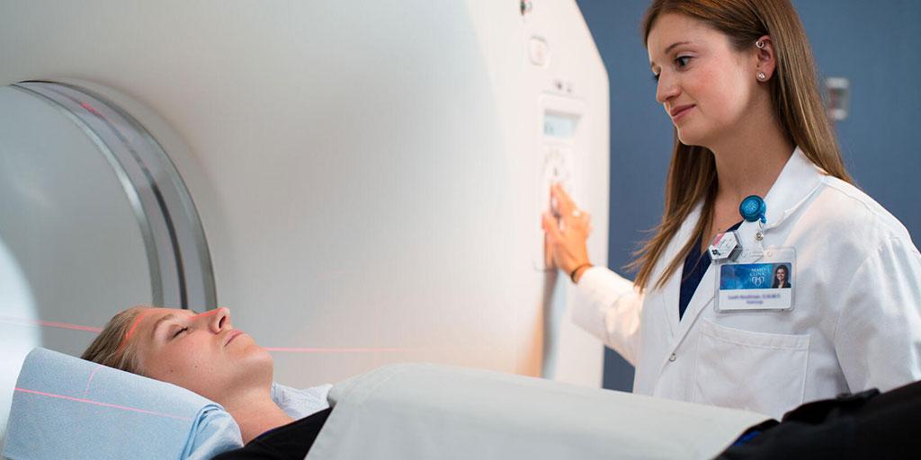 Positron emission tomography technologist with patient in a CT scan machine