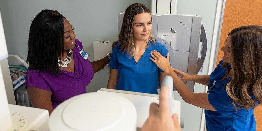 Radiography students practice correct positioning for a standing X-ray along with help from their instructor.