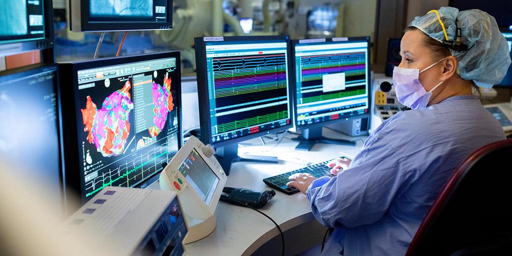 Nurse practitioner monitors heart rhythm data on a monitor in real-time.