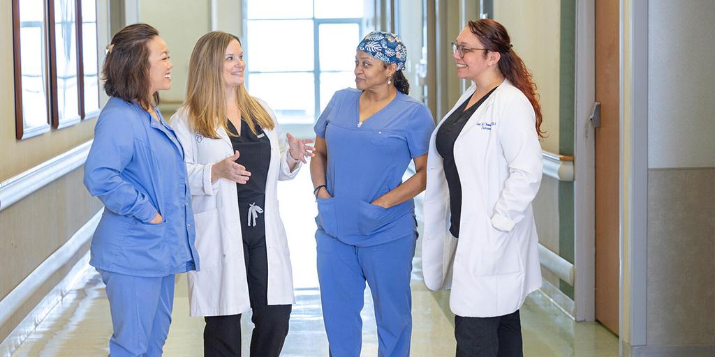 Nurse practitioners and nurses in endocrinology meet to discuss patient needs in a clinic hallway at Mayo Clinic