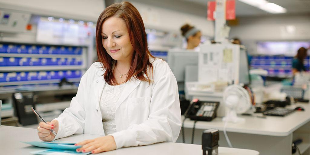 Pharmacist reviewing medication paperwork in pharmacy setting.
