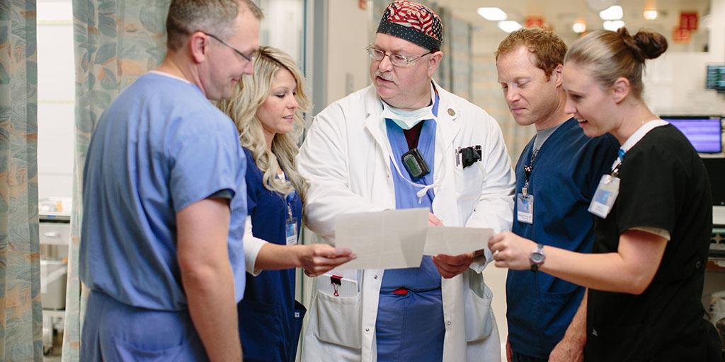 Group of nurses, pharmacists, and a physician discussing patient case.