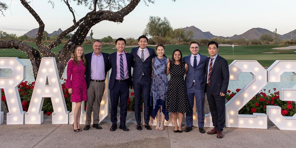 Five attendees pose for a photo with a large, light-up ‘Grad 2023’ sign during the Mayo Clinic School of Graduate Medical Education (MCSGME) graduation and award ceremony.