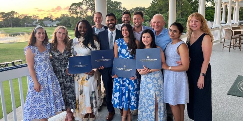 A gorup of residents pose outside holding their degrees at the 2024 graduation.