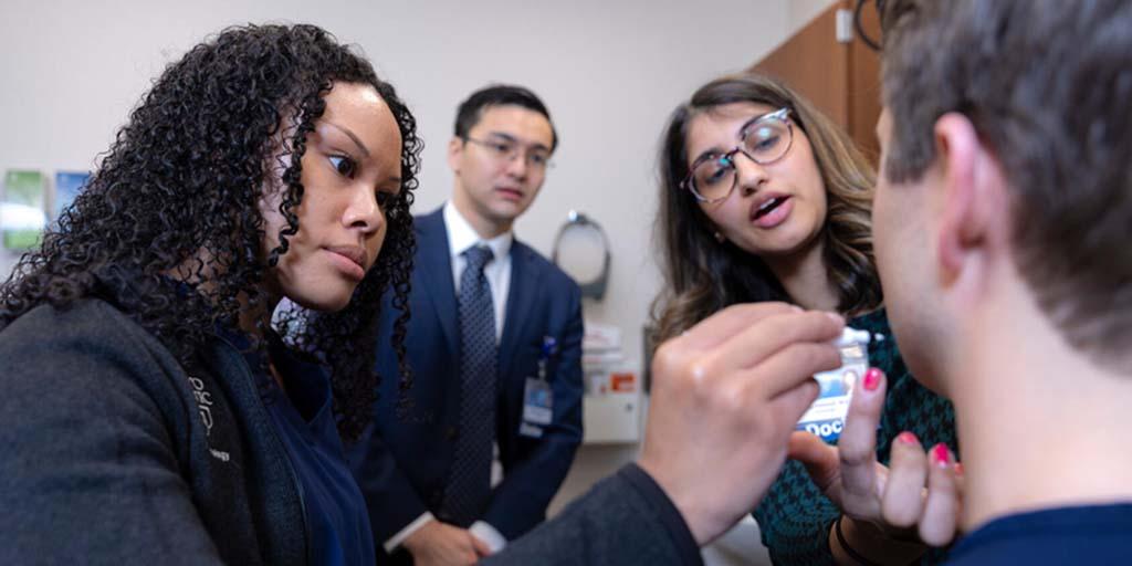 Hafsa Cantwell, MD, Dermatology consultant, guides a Dermatology resident in a cosmetic injection practice session while others observe.