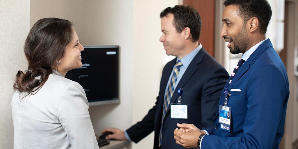 Three doctors standing in a hallway and having a discussion.