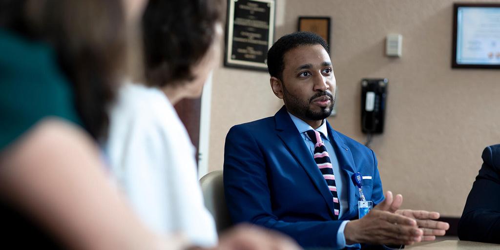 Three doctors have a discussion in a conference room.