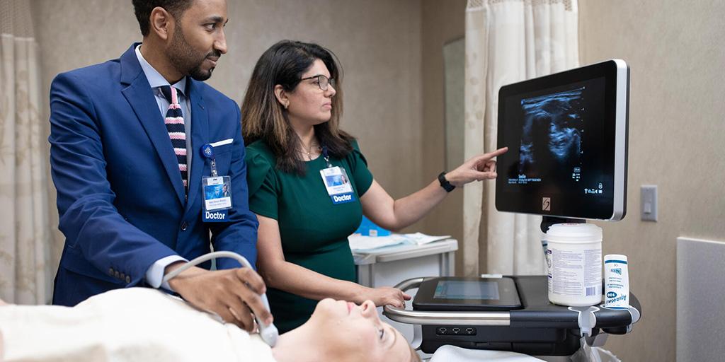 Two doctors discuss results while working with a patient.