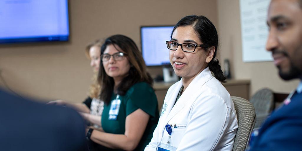 Four doctors have a discussion in a conference room.