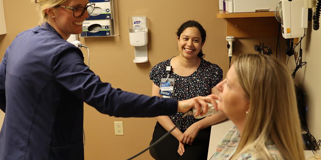 Doctor examining patient with onlooker.