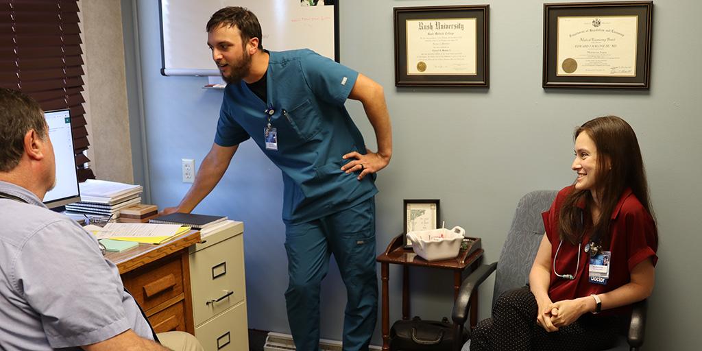Three people in office, resident looking at computer.