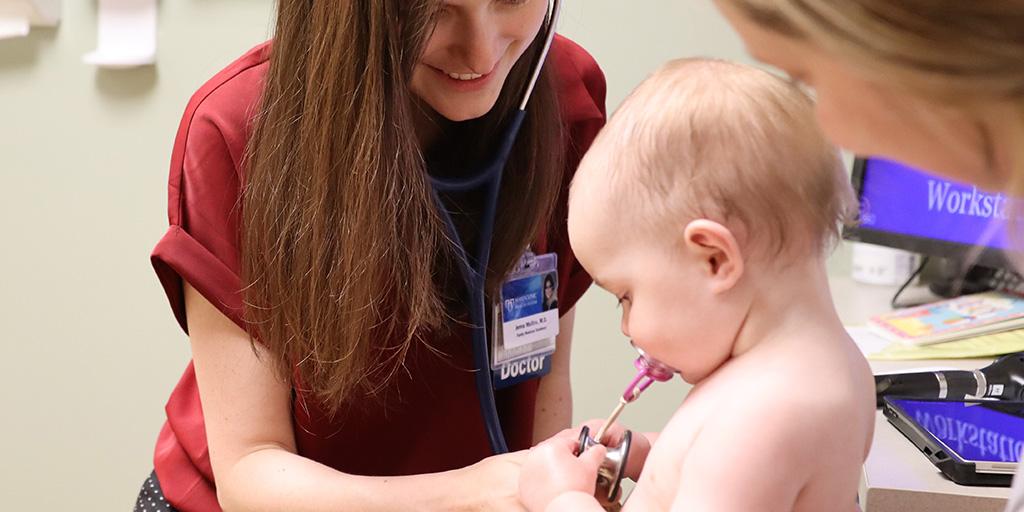 Doctor examines baby with stethoscope.