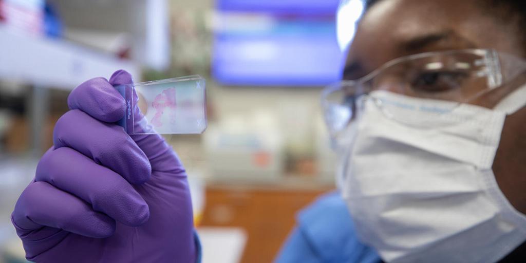Lab technician at Mayo Clinic looks at a specimen on a slide