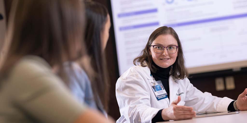 General Internal Medicine (GIM) fellows and a GIM Consultant at a conference table have a discussion.