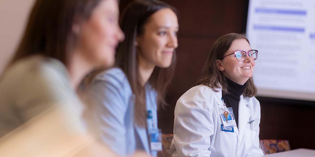 General Internal Medicine (GIM) fellows and a GIM Consultant at a conference table have a discussion.