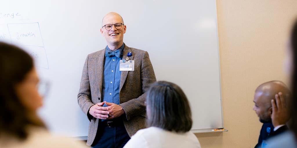 A General Internal Medicine (GIM) consultant lectures in front of a whiteboard to the gathered fellows.