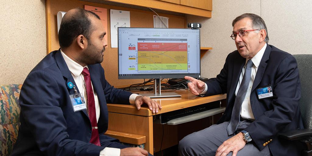 Two doctors in an office sitting at a desk and having a discussion.