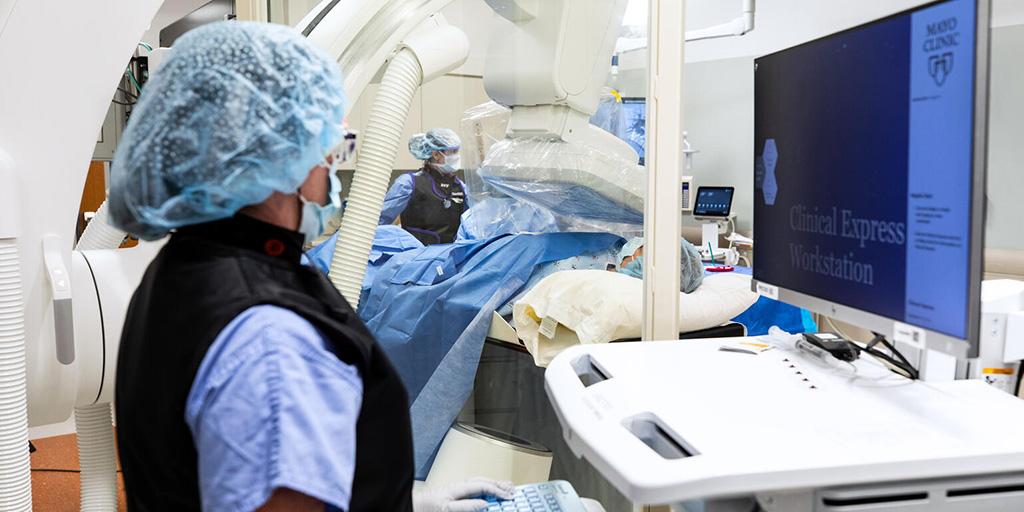 One doctor observing another doctor performing a procedure on a patient.