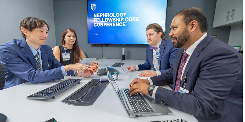 Nephrology medical professionals meet at a table in a conference room.