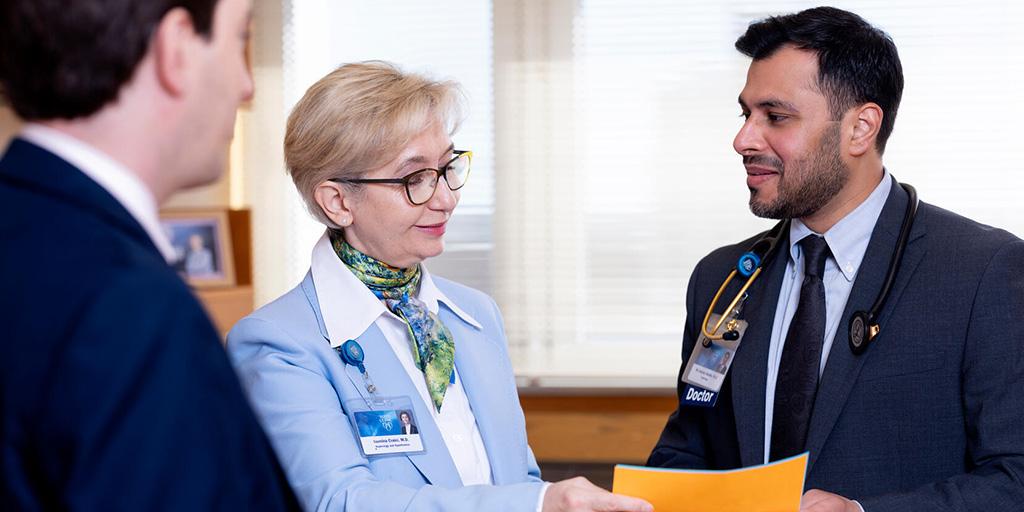 Iasmina Craici, MD, Nephrology consultant and fellowship program director, reviews paperwork with Nephrology fellows in an exam room.