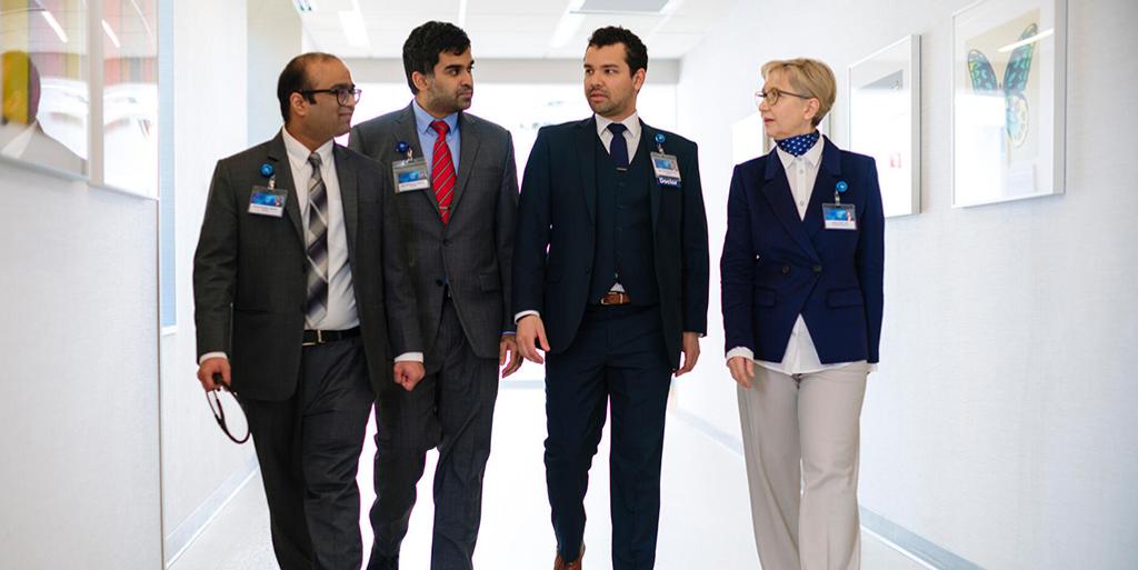 A group of four fellows talking and walking together down a hallway.