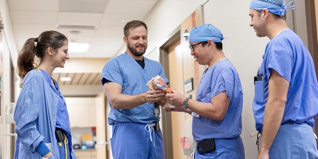 Four otolaryngology residents in hallway looking at model