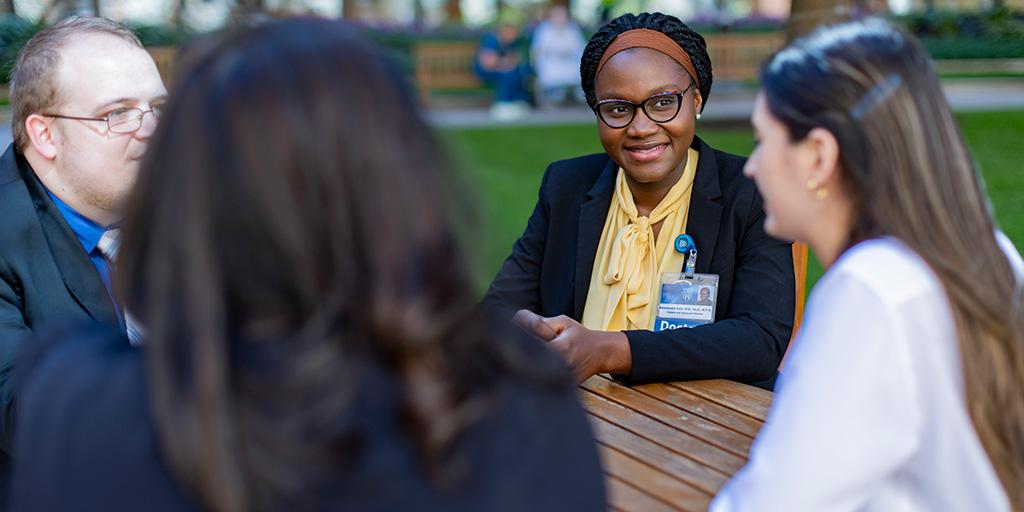 Four residents sitting outside at a table talking
