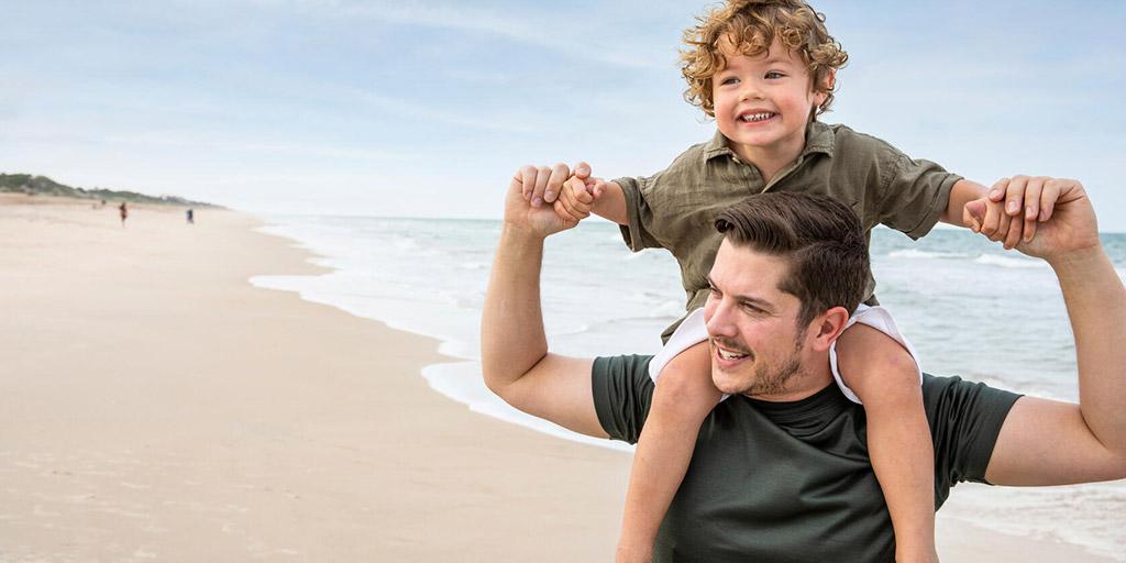 Young boy and his dad walk along the beach.