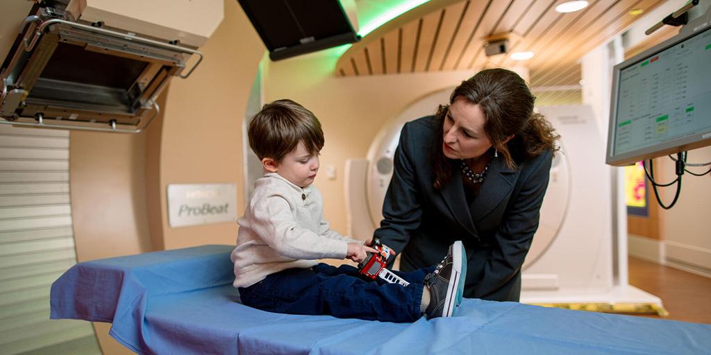 Doctor talking with young child on examination table.