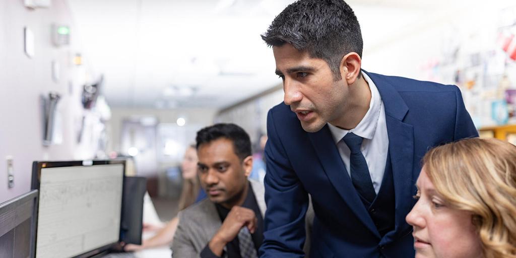 Specialists in the Sleep Medicine Department talk and work together in front of a computer workstation, while looking at a sleep study on the screen.