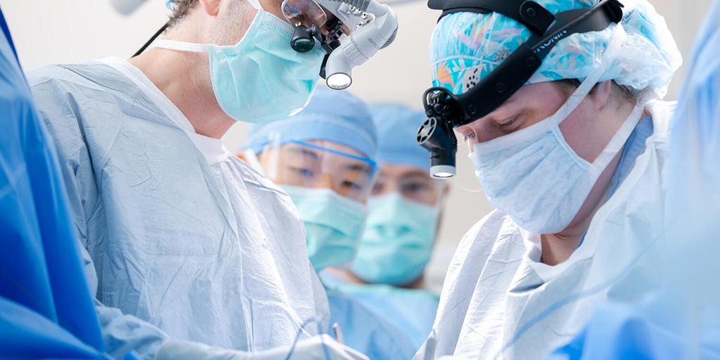 Boyd Viers, MD, PhD, Surgical Consultant in Urology, and surgical team members, wear loupe magnifiers and headlamp and focus toward the surgical field in the operating room.