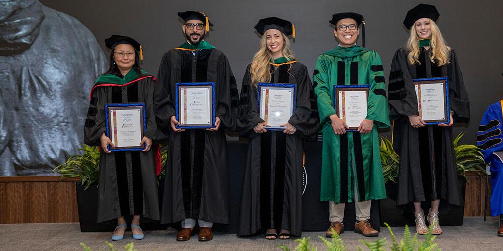 Distinguished staff award winners gather onstage for a photo during the Mayo Clinic Alix School of Medicine (MCASOM) commencement and reception.