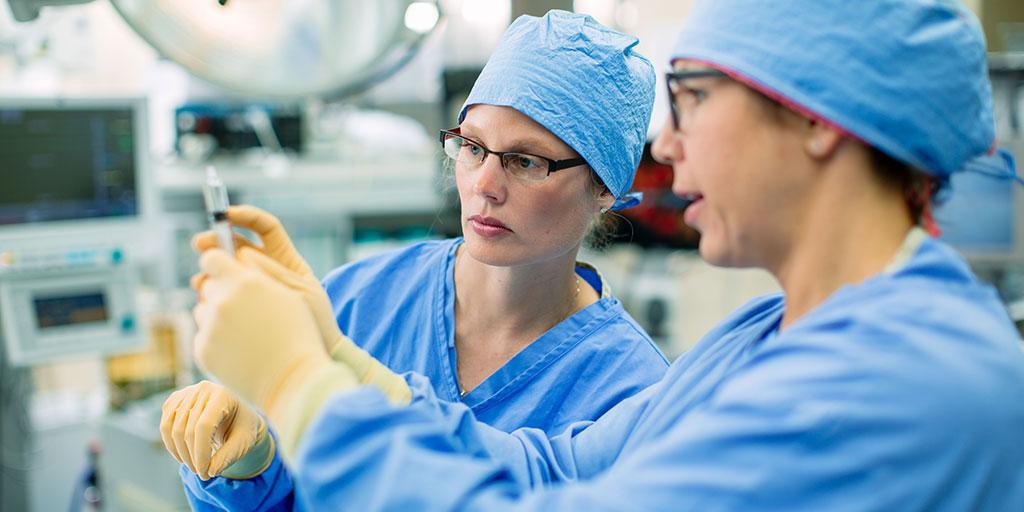 Physicians in operating room preparing a medication in a syringe