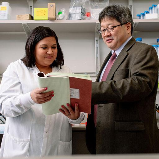 A faculty mentor with a trainee looking at paperwork in the lab