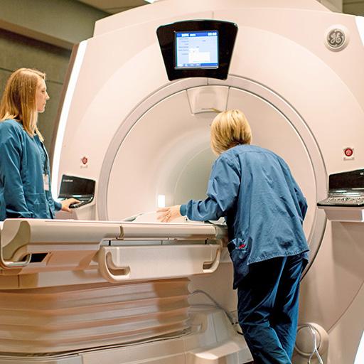 Two MRI technologists work with an MRI scanner.