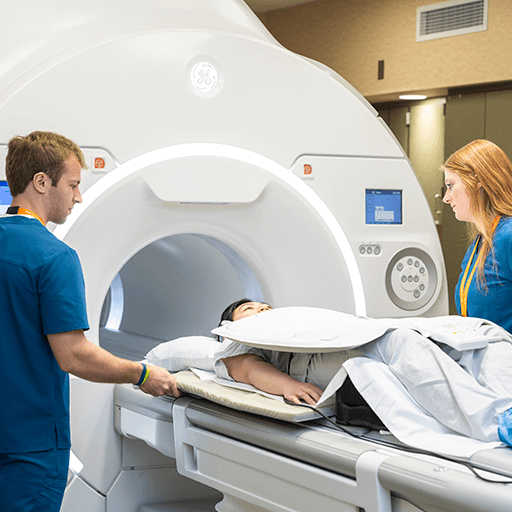 Two people helping patient into scanner