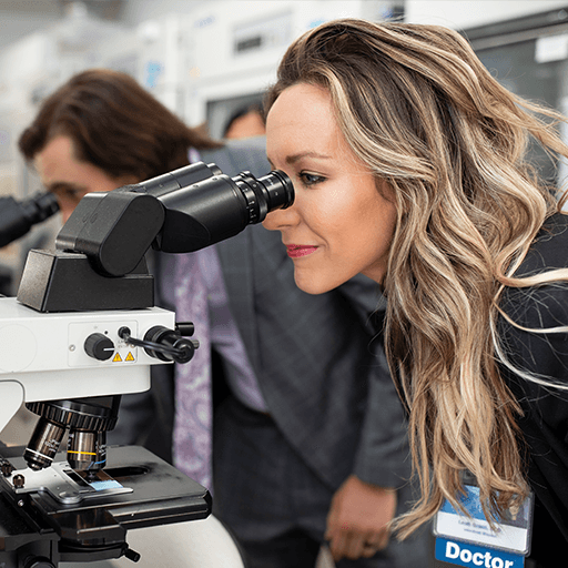 A physician assistant looks into a microscope