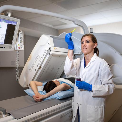A nuclear medicine technician prepares to scan a patient in a machine.