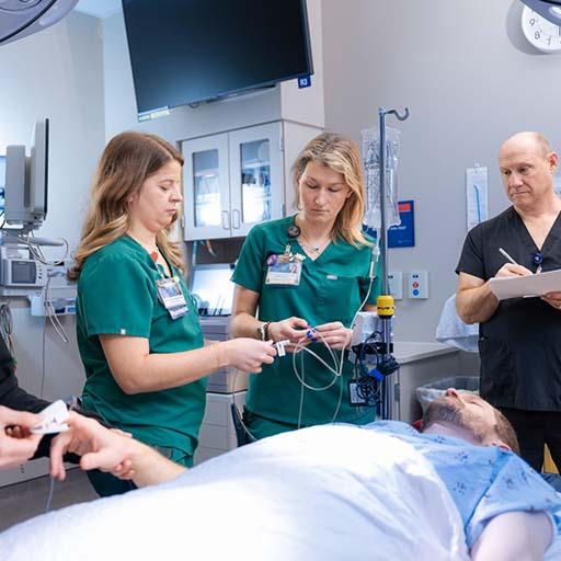 Two ER nurses and an ER tech work together to care for a patient.